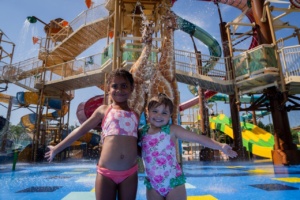Two girls in front of an animal-themed aquatic play structure