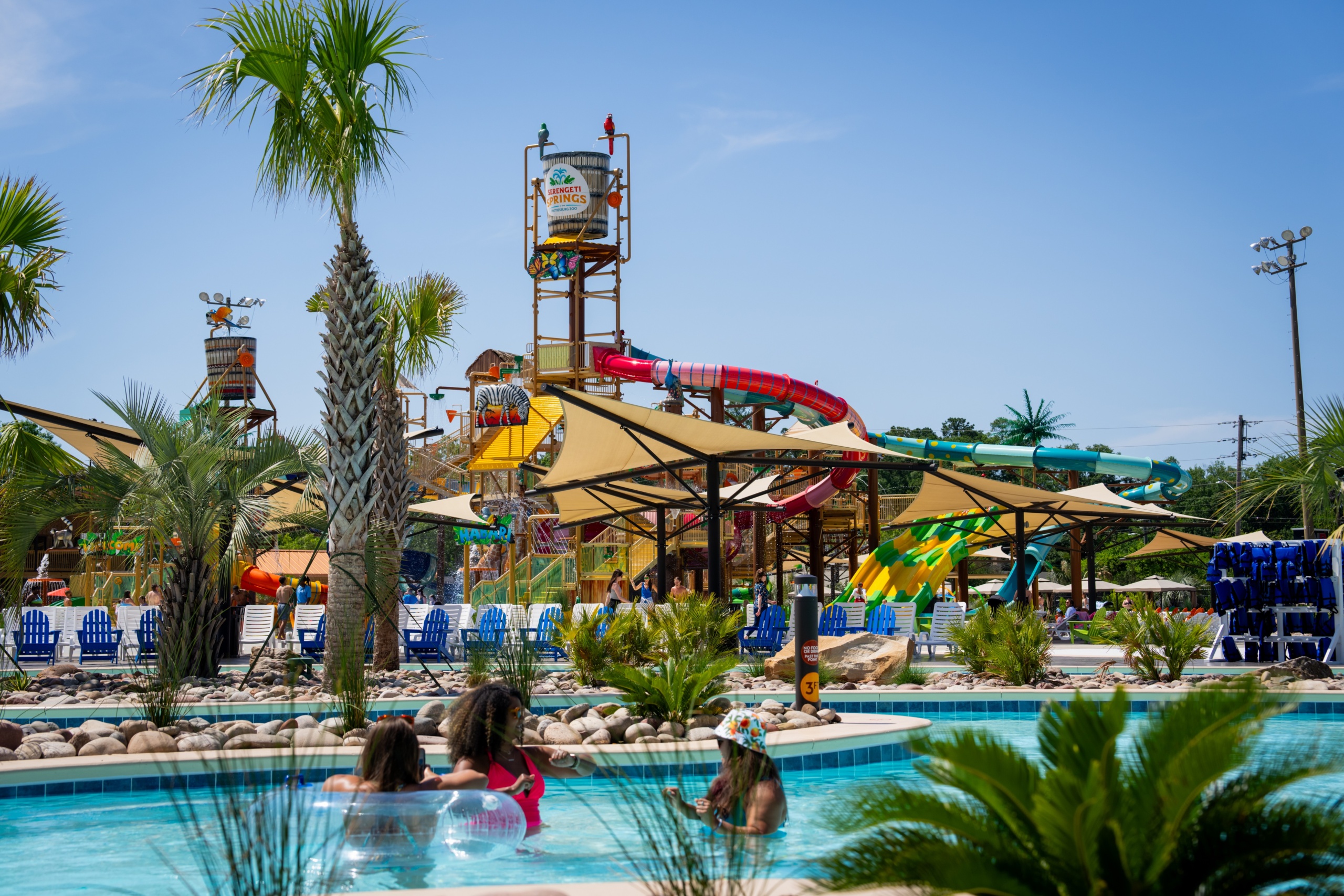 A lazy river at a water park with an aquatic play structure in the background