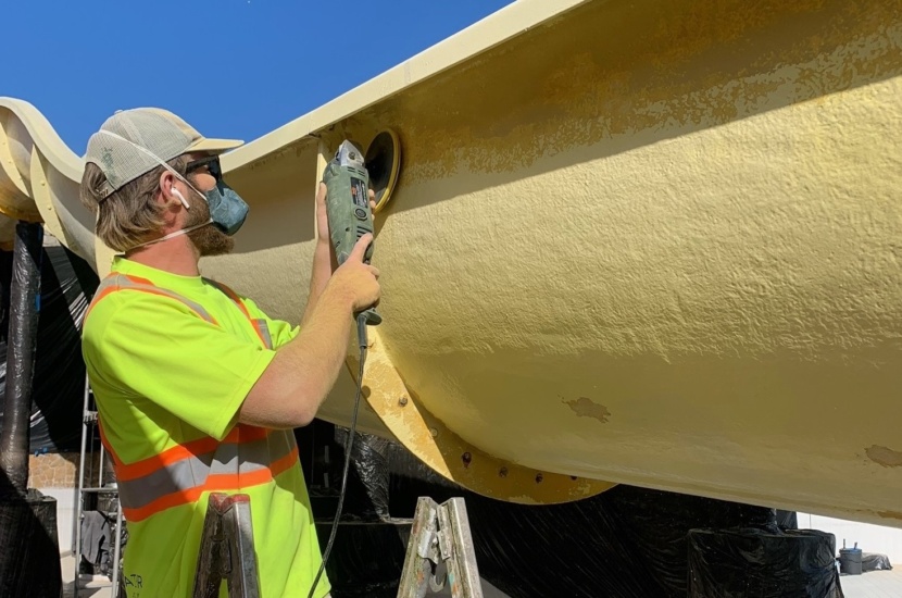 Man working on resurfacing a yellow water slide