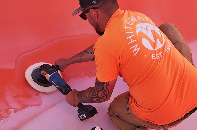 A man in an orange shirt holding a buffer buffing a water slide