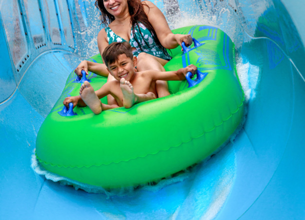 Small child and an adult in an inner tube on a water coaster